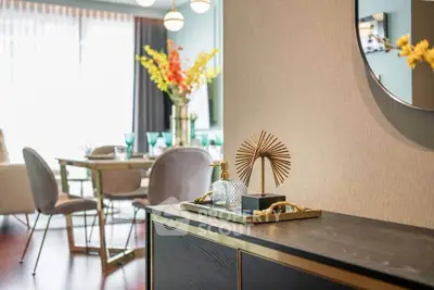 Elegant modern living room with stylish decor and dining area, featuring luxurious furniture and vibrant floral accents.