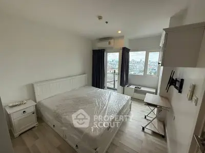 Modern bedroom with city view, featuring a large bed and wall-mounted TV.