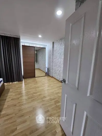 Spacious bedroom with wooden flooring and large mirrored wardrobe