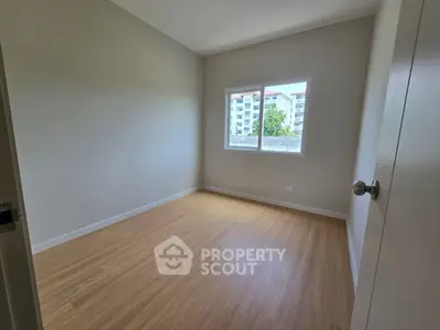 Bright empty bedroom with wooden flooring and large window view