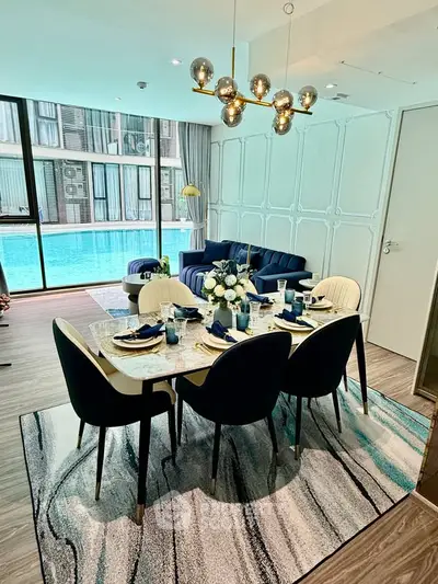 Luxurious dining area with pool view, elegant decor, and modern lighting in a stylish apartment.