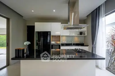Modern kitchen with sleek black countertops and stainless steel appliances in a bright, open layout.
