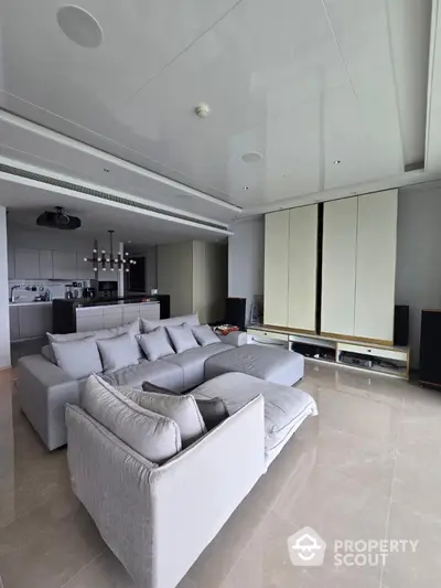 Spacious modern living room with plush gray sectional sofa and sleek open kitchen