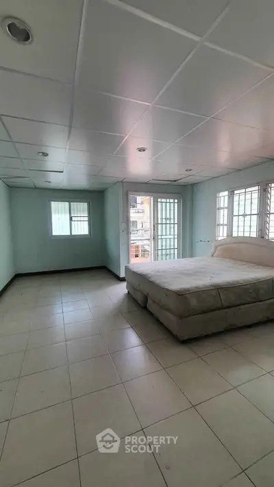 Spacious bedroom with large windows and natural light in modern apartment