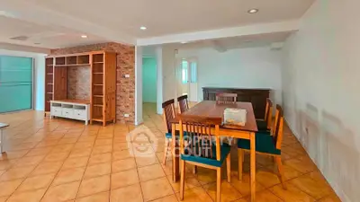 Spacious open-plan living and dining area with stylish wooden furniture and brick accent wall.