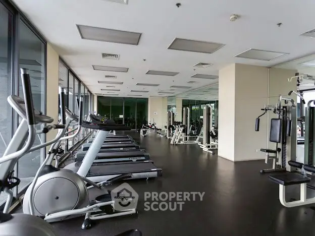 Spacious modern gym with state-of-the-art equipment and large windows for natural light.