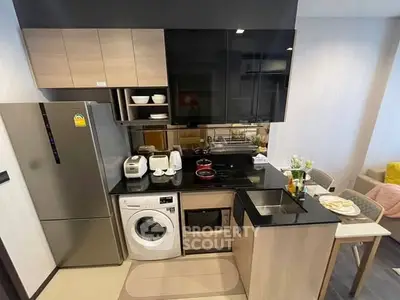 Modern compact kitchen with appliances and dining area in stylish apartment.