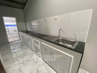 Modern kitchen with sleek black countertops and white cabinetry, featuring a gas stove and spacious layout.