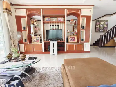 Spacious living room with elegant wooden entertainment center and cozy seating area.