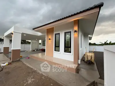Modern single-story house with sleek design and spacious outdoor area under cloudy sky.