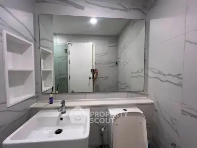 Modern bathroom with sleek design and large mirror, featuring elegant marble tiles.