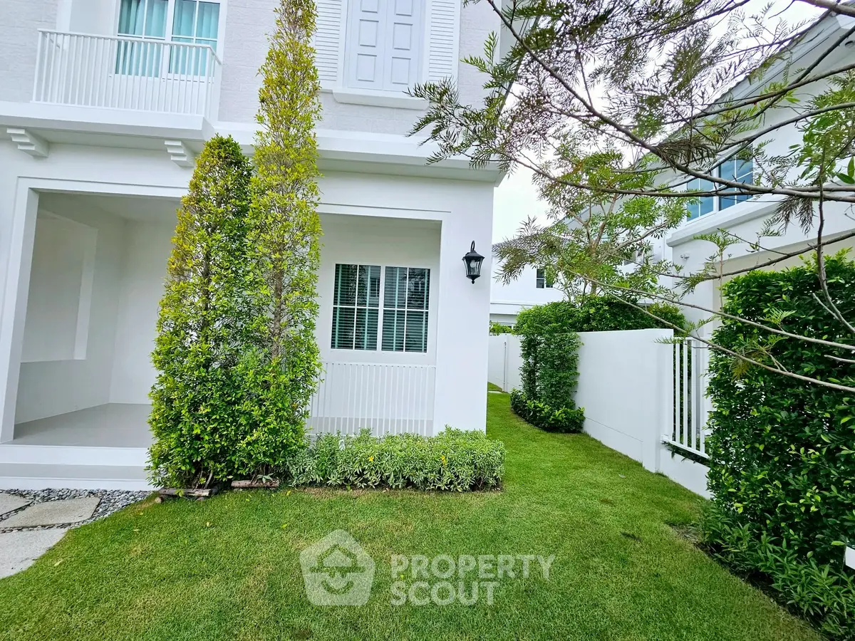 Charming white house exterior with lush green garden and elegant architectural details.