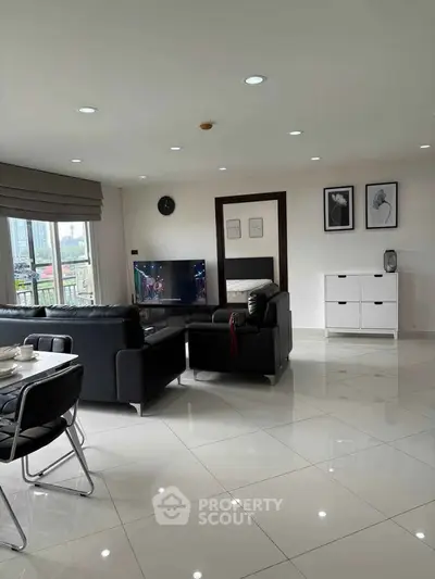 Spacious modern living room with sleek black leather sofas and large windows.