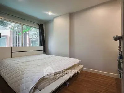 Cozy bedroom with modern decor and large window offering natural light