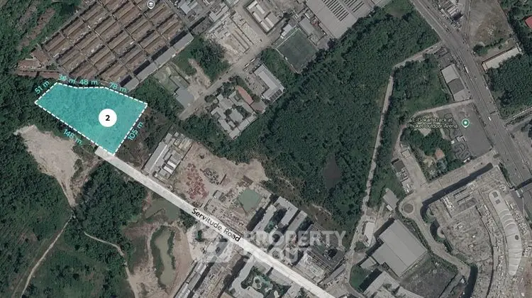 Aerial view of industrial land plot with road access and surrounding greenery.