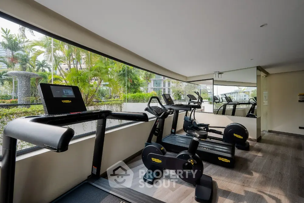 Modern gym with state-of-the-art equipment and large windows offering lush garden views.
