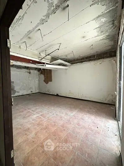 Spacious unfinished room with tiled floor and exposed ceiling, ideal for renovation.