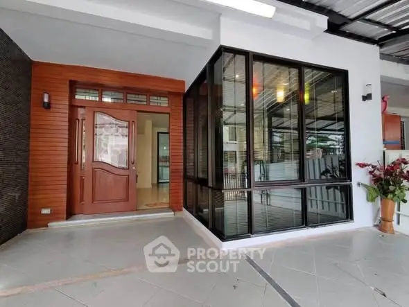 Modern home entrance with stylish wooden door and large glass windows.