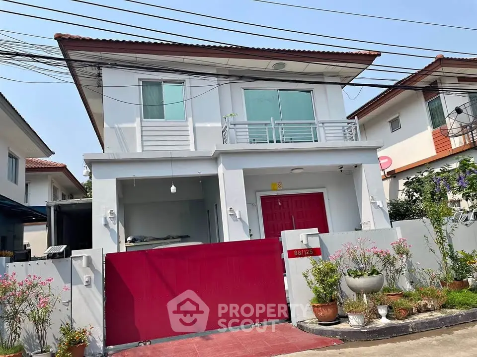 Charming two-story house with red gate and modern facade in a serene neighborhood.