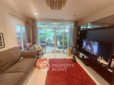 Spacious living room with large windows and cozy seating area, perfect for relaxation.