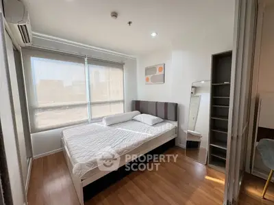 Modern bedroom with large window and stylish decor in a bright apartment.