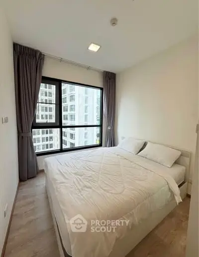 Bright and cozy bedroom with large window and modern decor in urban apartment.