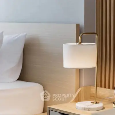Modern bedroom with stylish lamp and wooden headboard, perfect for a cozy retreat.