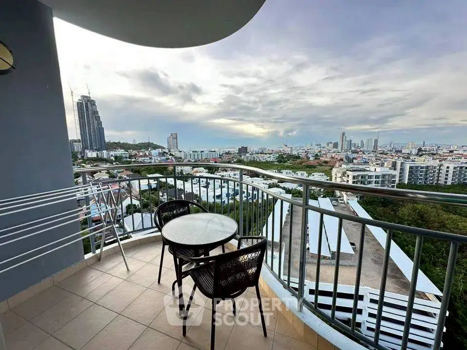Stunning cityscape view from a modern balcony with seating area, perfect for relaxation.