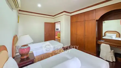 Spacious bedroom with twin beds and elegant wooden furniture in a cozy apartment.