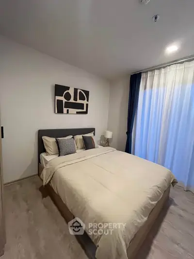 Modern bedroom with stylish decor and natural light, featuring a comfortable bed and elegant curtains.