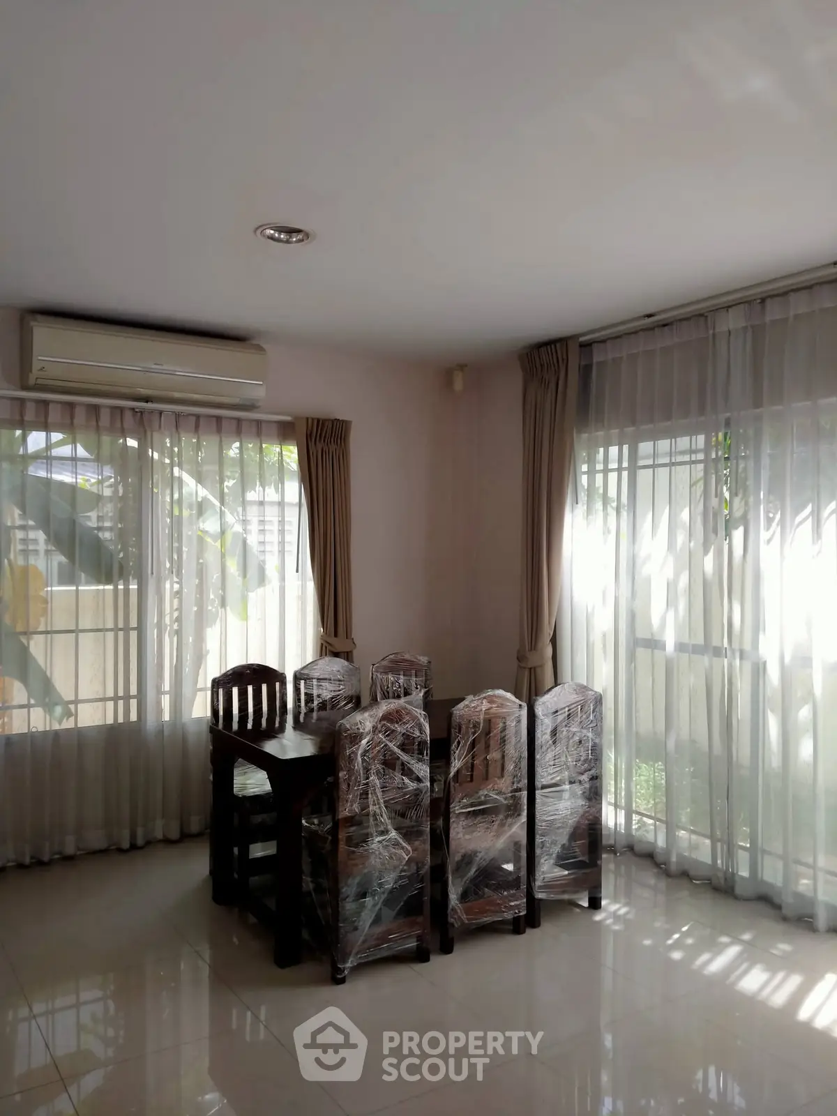 Bright dining area with natural light and air conditioning, featuring a wooden table and chairs.