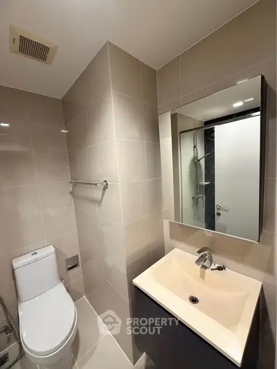 Modern bathroom with sleek fixtures and neutral tiles, featuring a stylish vanity and mirror.