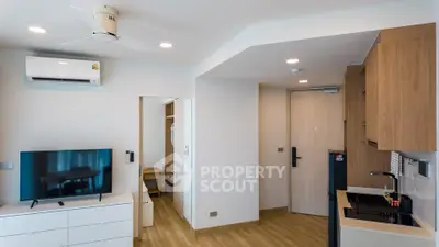 Modern apartment interior with open kitchen and living area, featuring sleek wooden cabinetry and contemporary design.