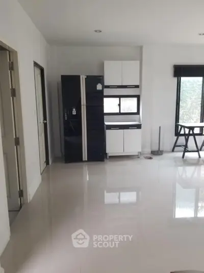 Modern kitchen with sleek black fridge and minimalist white cabinets.