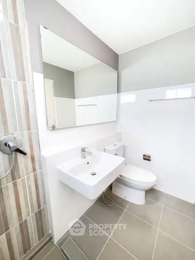 Modern bathroom with sleek fixtures and neutral tiles, featuring a large mirror and contemporary design.