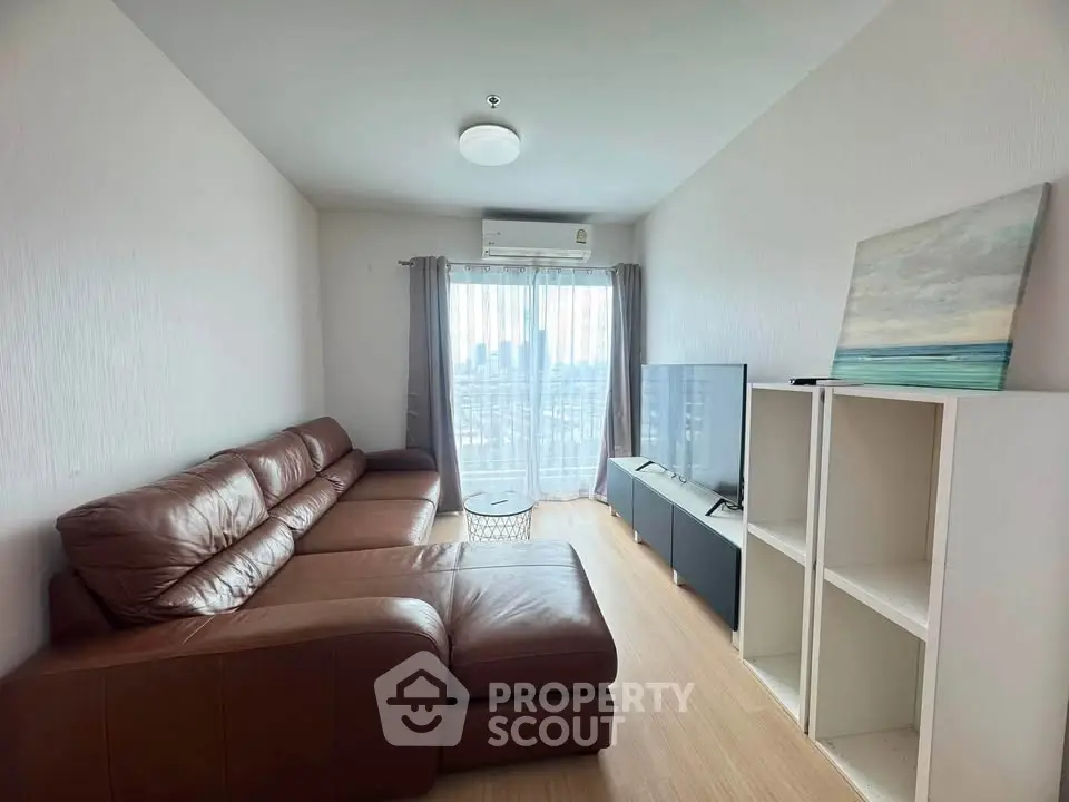 Modern living room with leather sofa and city view, featuring sleek TV setup and natural light.