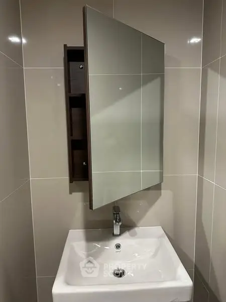 Modern bathroom with sleek sink and mirrored cabinet in stylish real estate property.