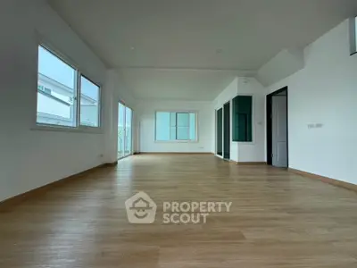Spacious modern living room with large windows and wooden flooring, perfect for natural light and open living.