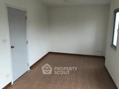 Spacious empty room with tiled floor and window, ideal for customization.