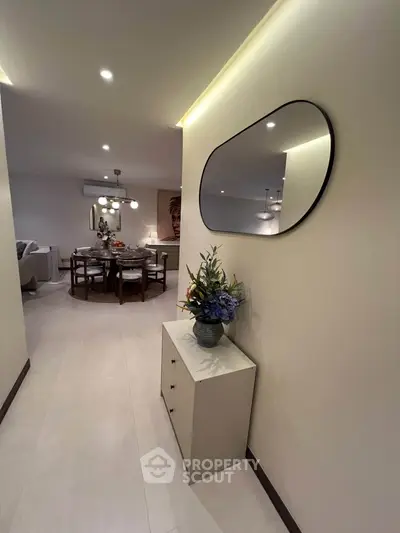 Stylish modern apartment interior with elegant dining area and decorative mirror in hallway.