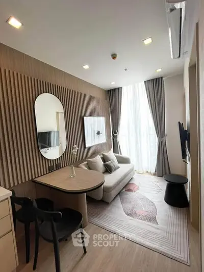 Modern living room with stylish decor and natural light, featuring a cozy sofa and elegant wall paneling.