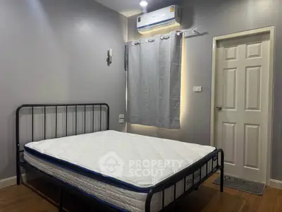 Modern bedroom with minimalist design featuring a metal bed frame and air conditioning.