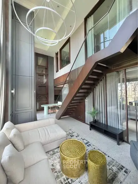 Luxurious modern living room with high ceilings and elegant staircase in a duplex apartment.