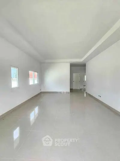 Spacious empty room with glossy tiled floor and large windows, ideal for customization.