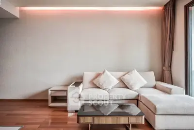 Modern living room with elegant sofa and stylish coffee table, featuring ambient lighting and wooden flooring.