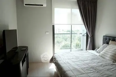 Bright bedroom with large window and modern furnishings in a high-rise apartment.