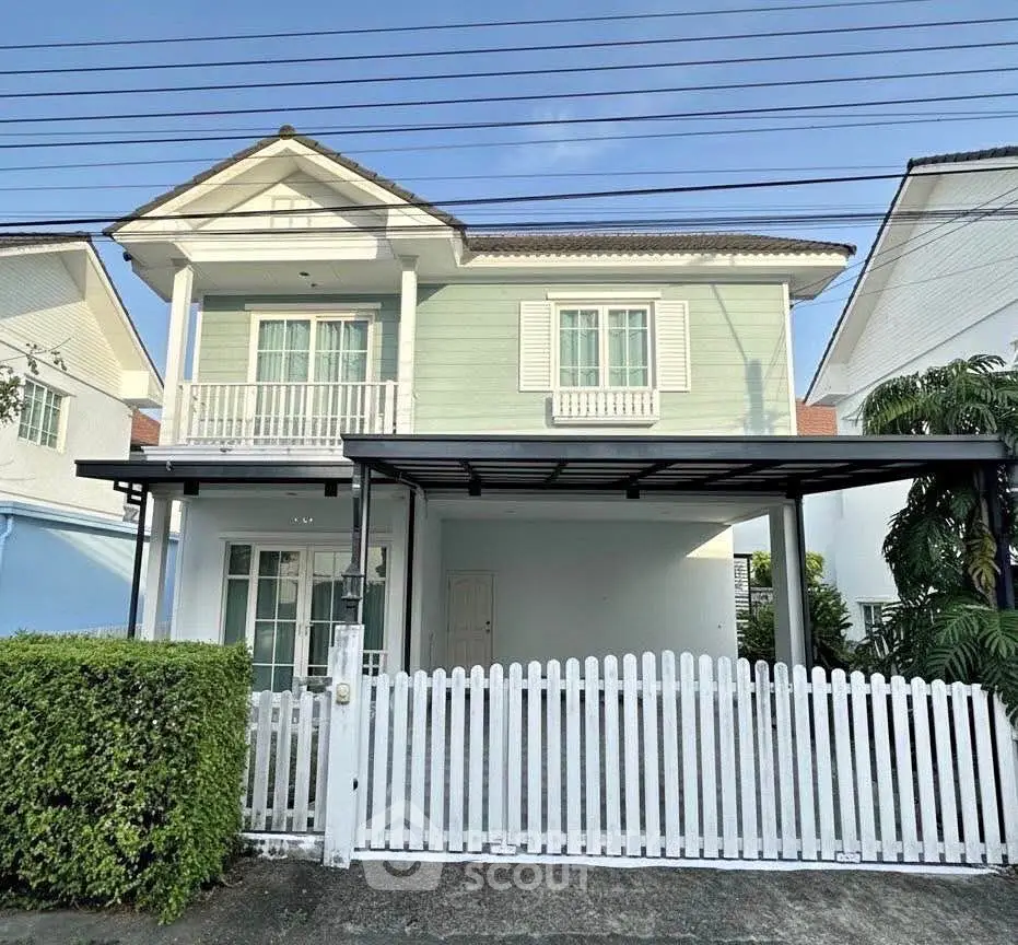 Charming two-story house with white picket fence and lush greenery
