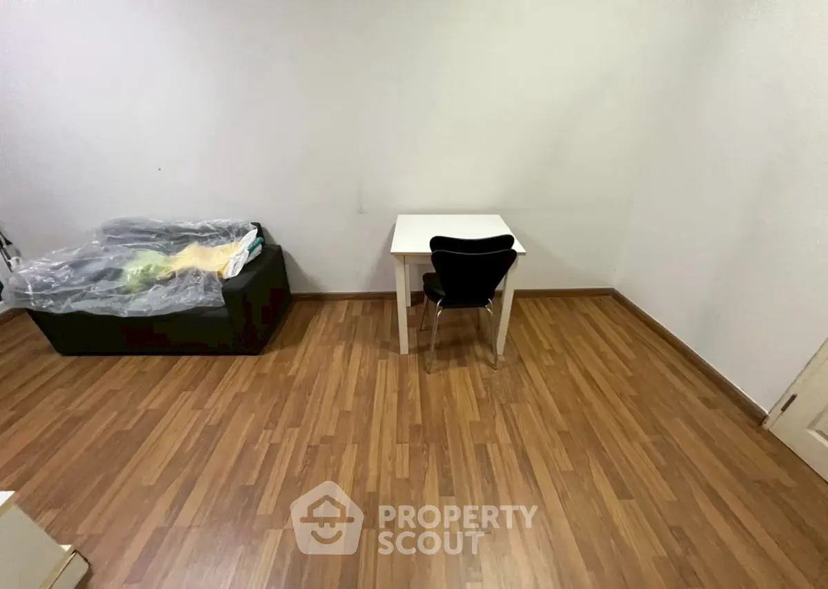 Minimalist room with wooden flooring, small table, and chair, ideal for compact living spaces.