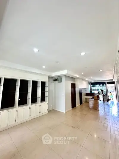 Spacious open-plan living area with built-in shelving and modern kitchen.