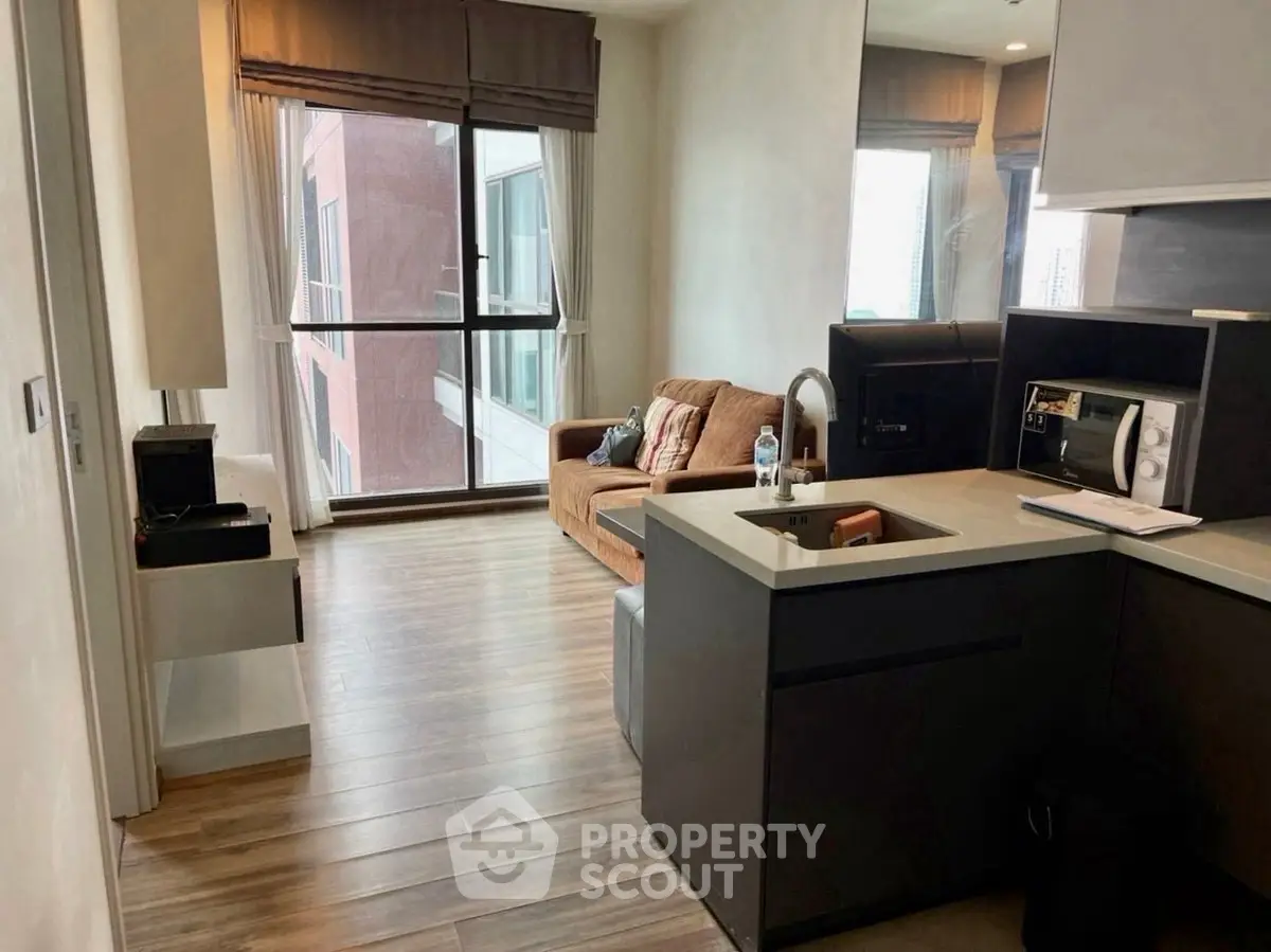 Modern apartment with open kitchen and cozy living area featuring large windows and stylish decor.